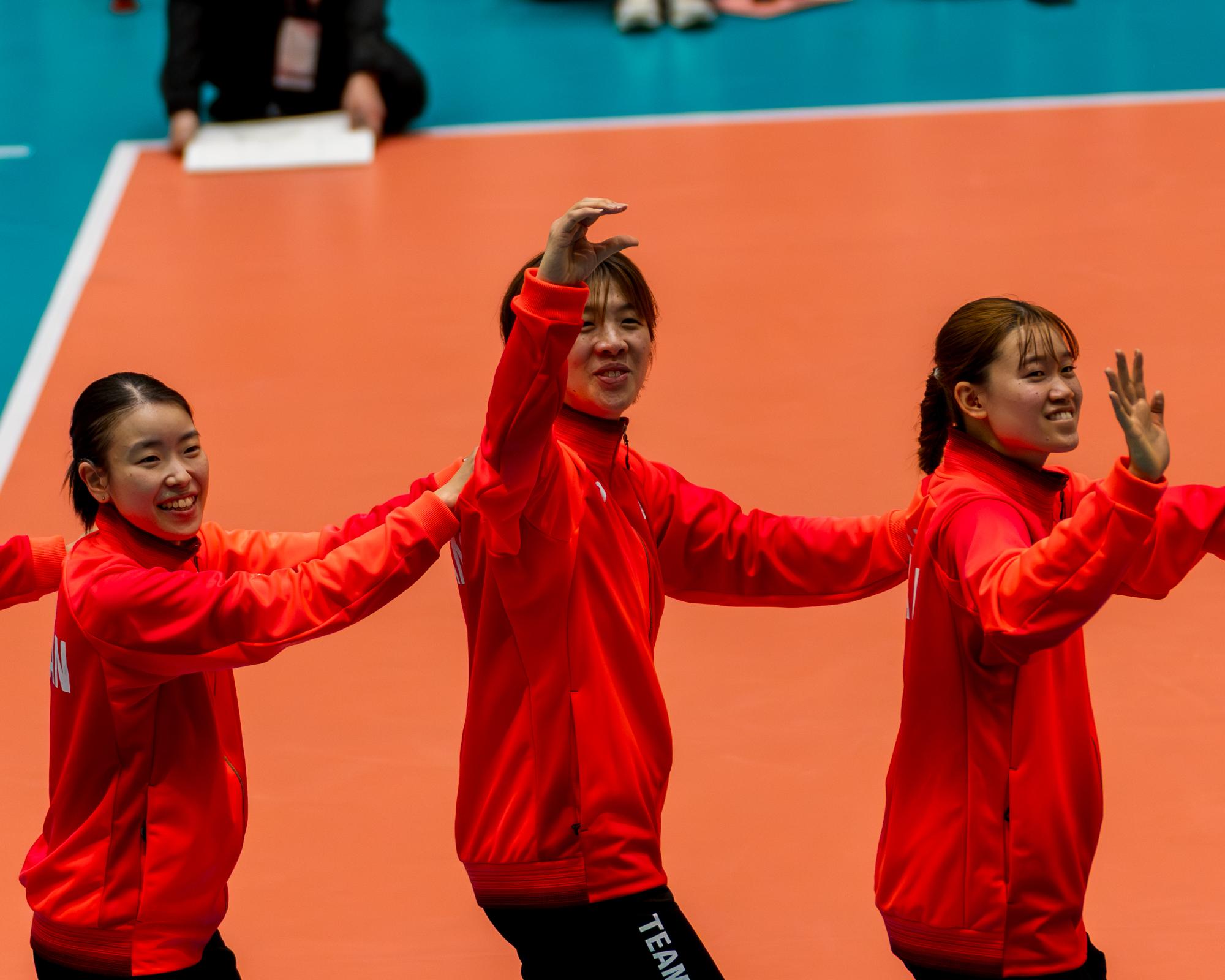 表彰式で両腕を前の人の肩に乗せながら入場する選手らの写真