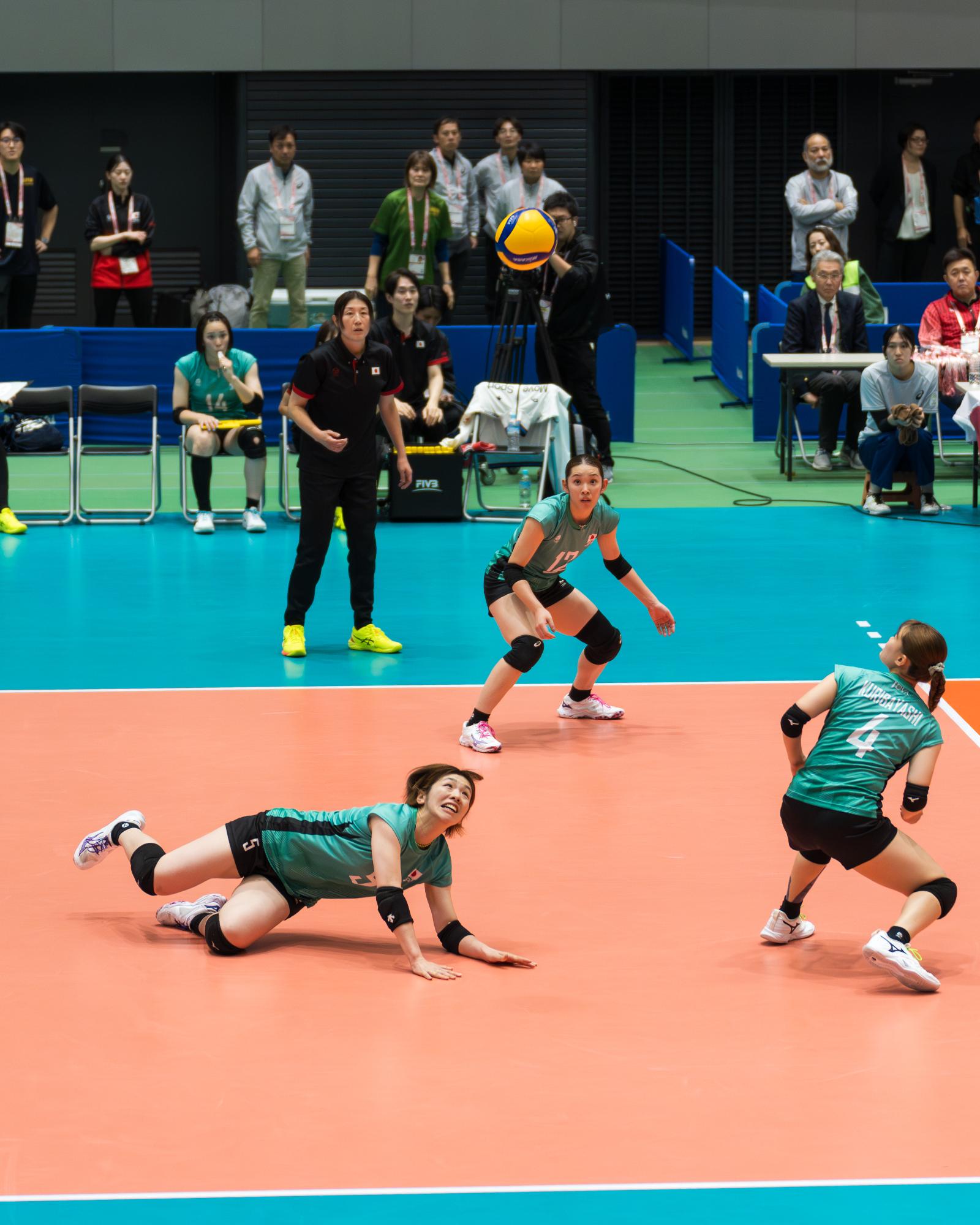 スライディングしながらレシーブをする尾塚選手の写真