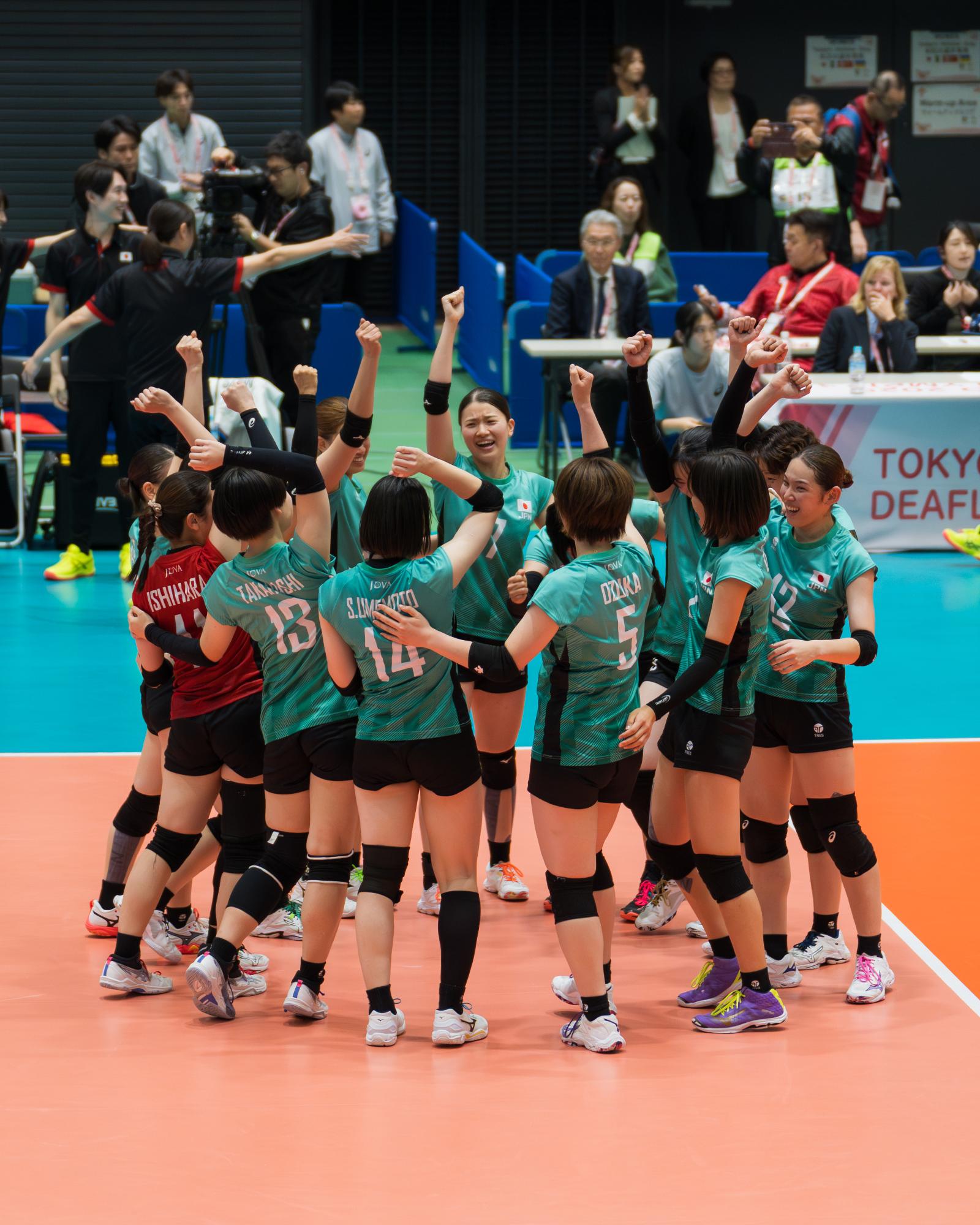 コートでチーム全員で円陣を組み右腕をあげる選手らの写真