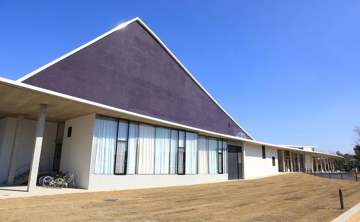 青空の下に三角屋根と大きい窓がある阿久根市民交流センター（風テラスあくね）外観の写真