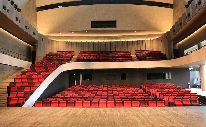広々とした空間に赤い椅子が並ぶ、阿久根市民交流センター（風テラスあくね）ホールの写真