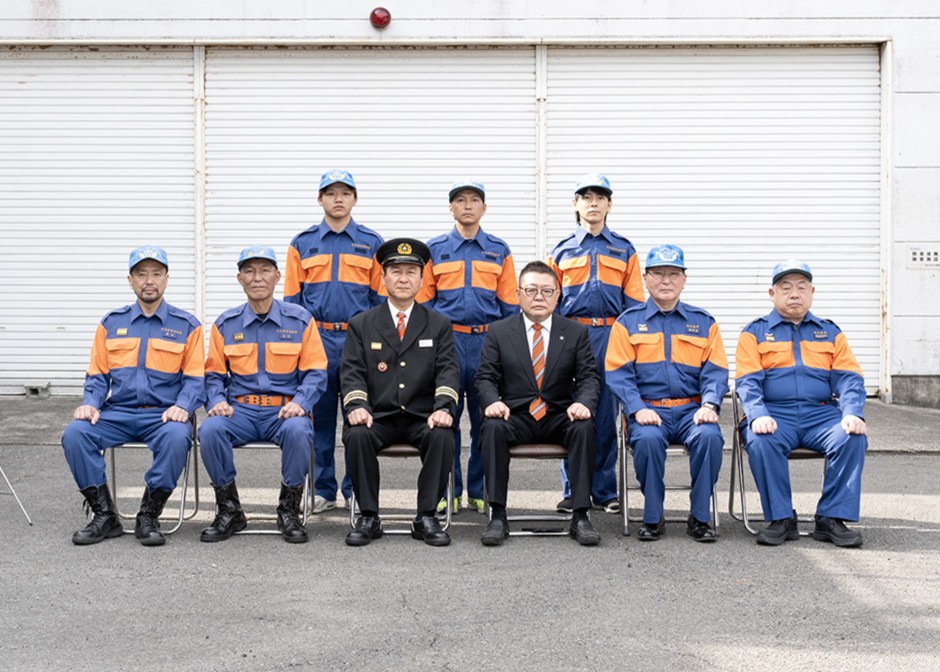 西平市長と松崎副市長、総務課長、消防団長、副団長と新入団員の集合写真