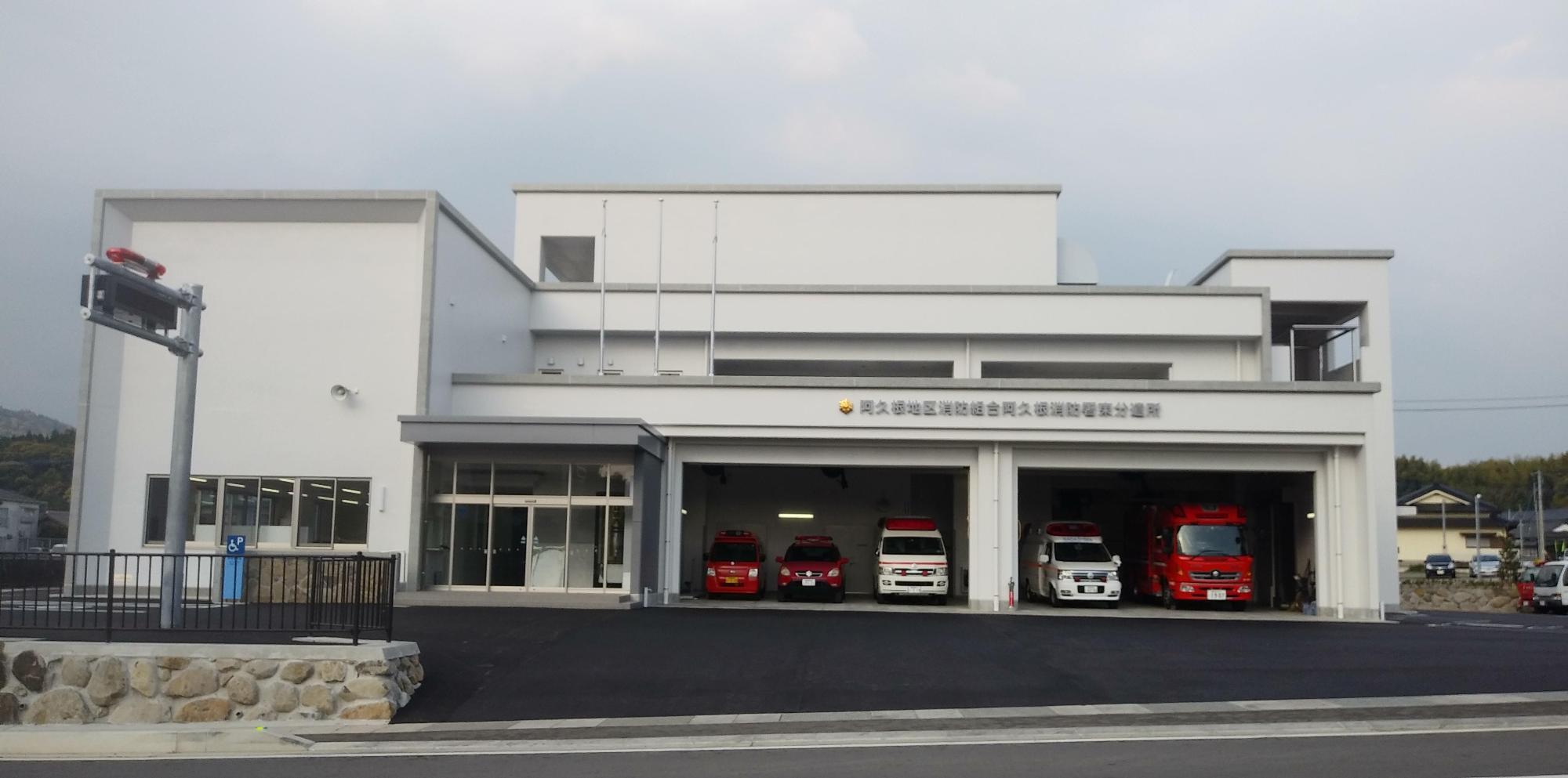 1階の車庫に合計6台の消防車や救急車が並ぶ白を基調とした阿久根消防署東分遣所の外観の写真