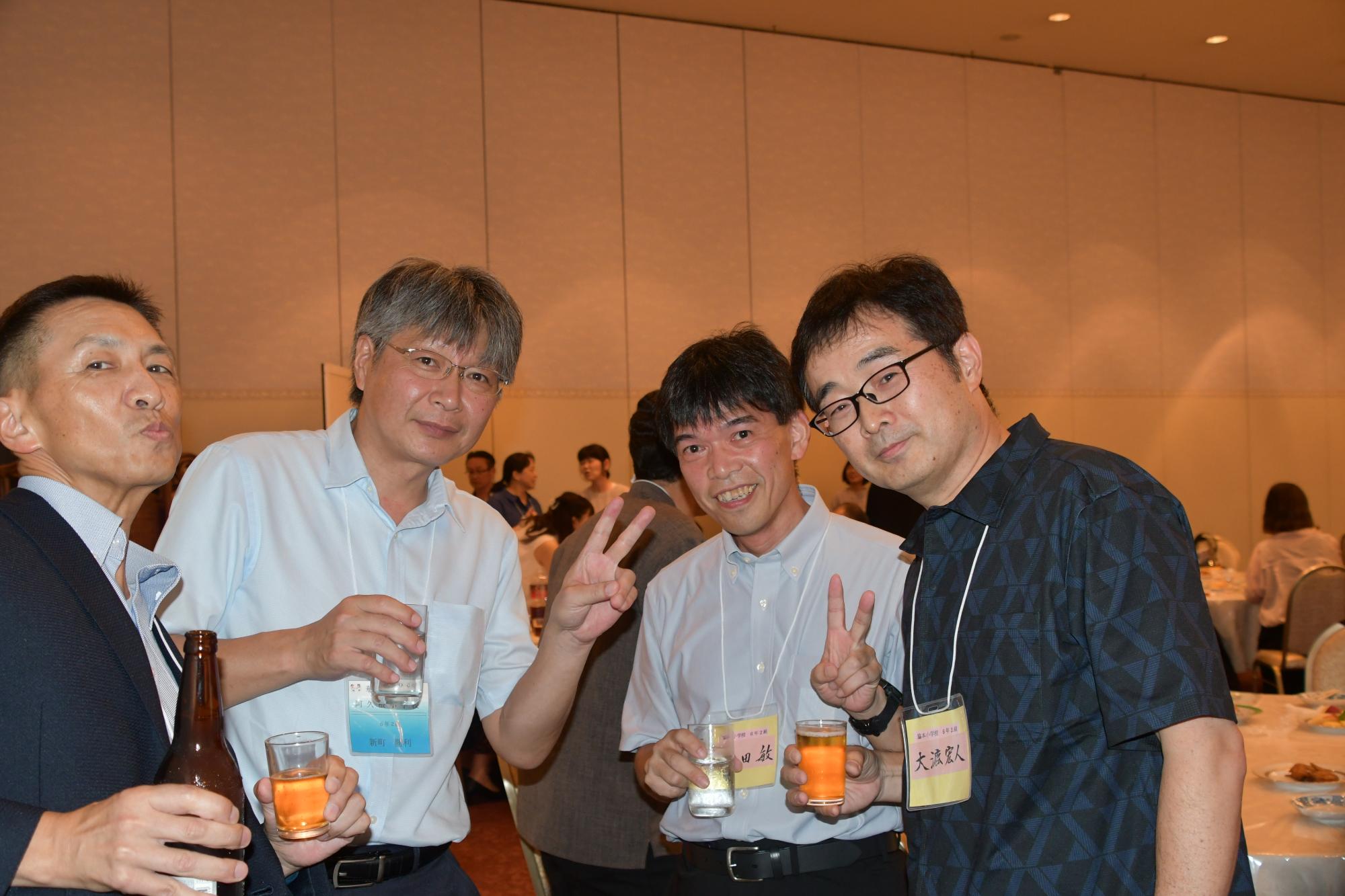 参加者たちの写真（飲み物を片手に写る4人の男性）