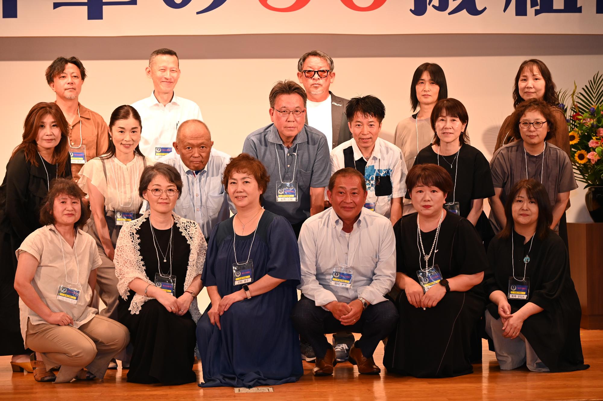 「歓迎 華の50歳組」と書かれた横断幕の前に並ぶ参加者たちの集合写真（折多小）