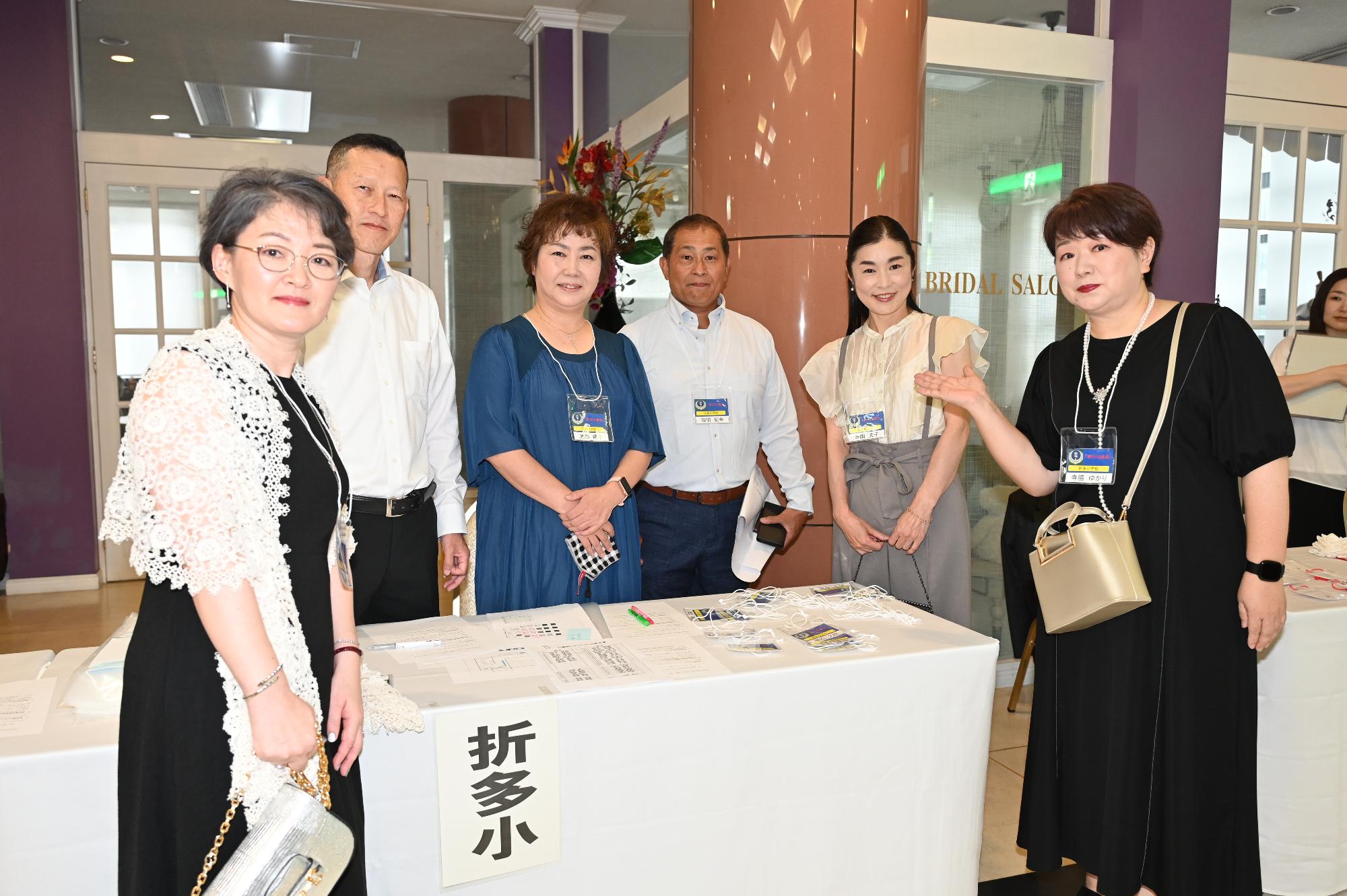 折多小出身の参加者たちの写真（受付で並ぶ6人の男女）