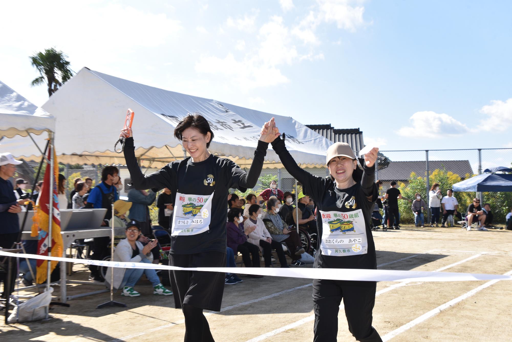 リレーで手をつないでゴールをする女性2人組の写真