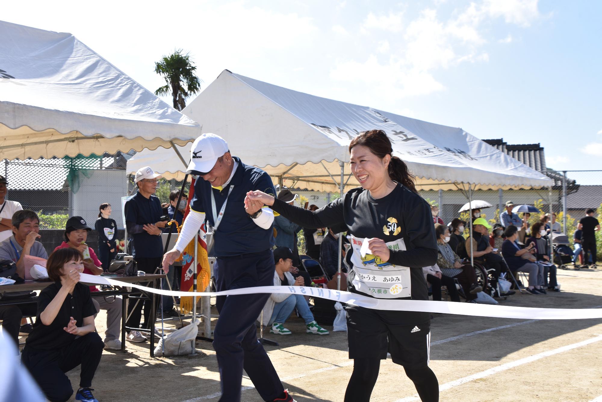 リレーで手をつないでゴールをする男女2人組の写真