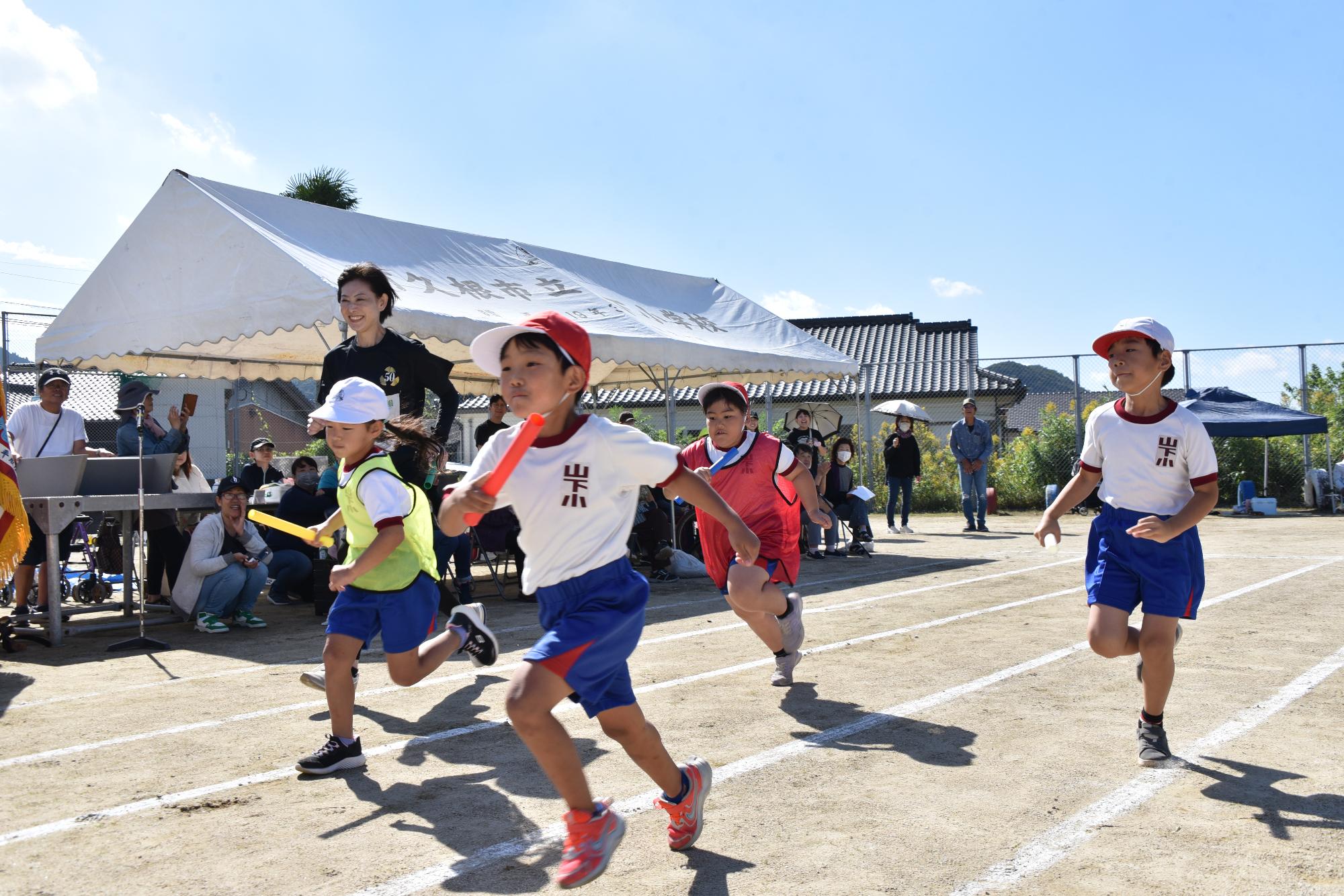 小学生4人とともにリレーで走る参加者の写真