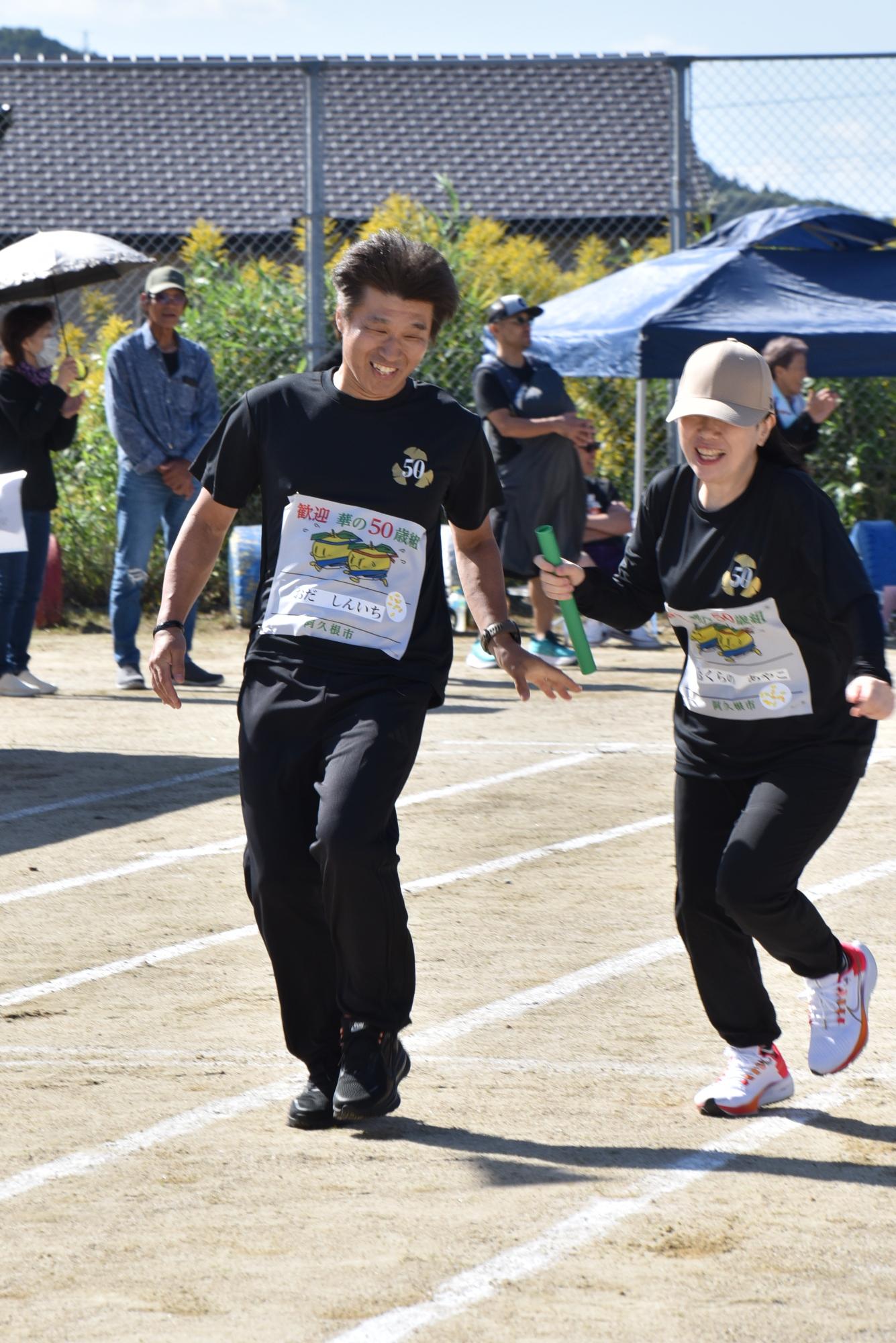 リレーでバトンをつなぐ男女2人の参加者の写真