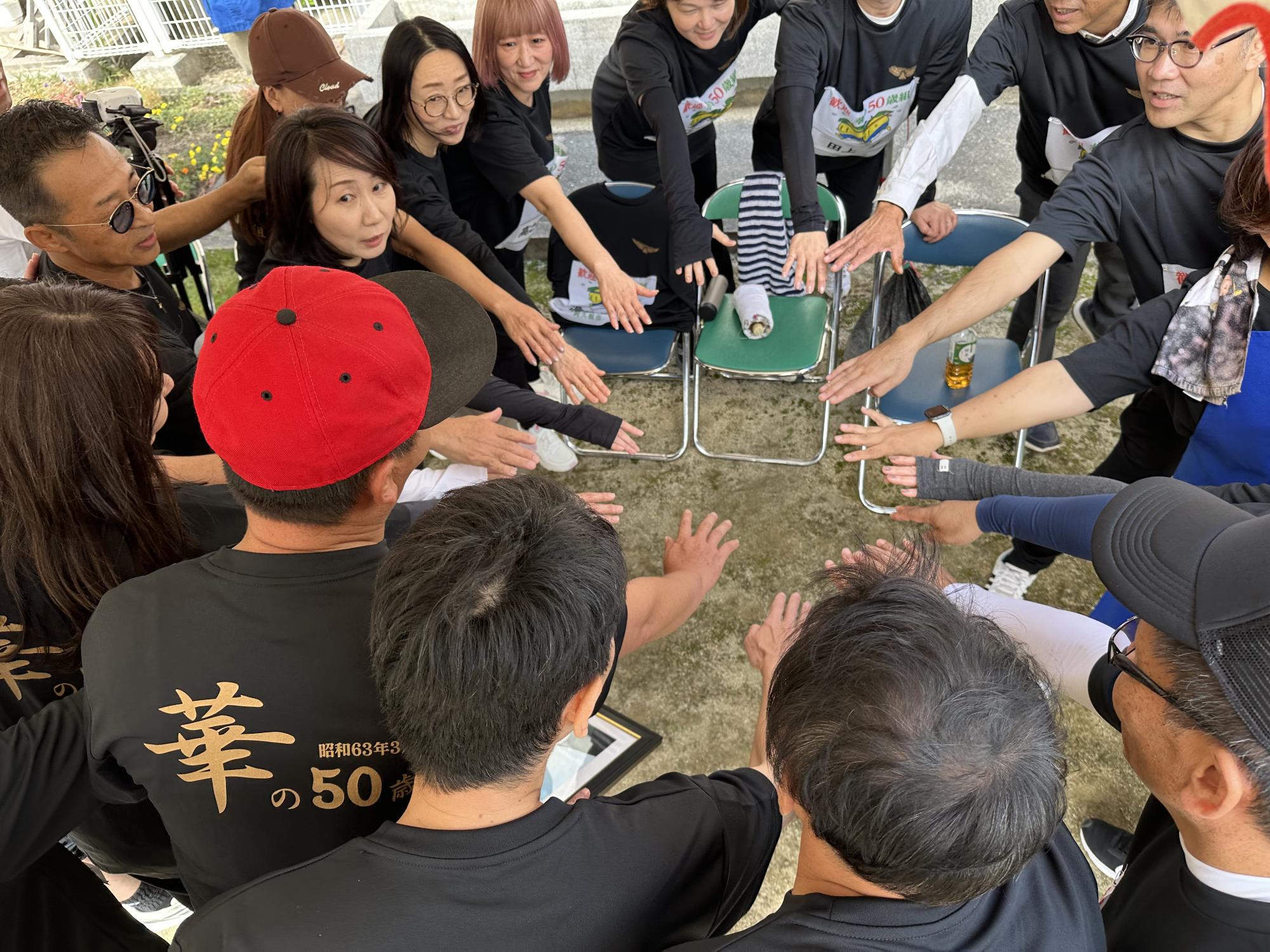 入場前に円陣を組む西目小学校華の50歳組の参加者の写真