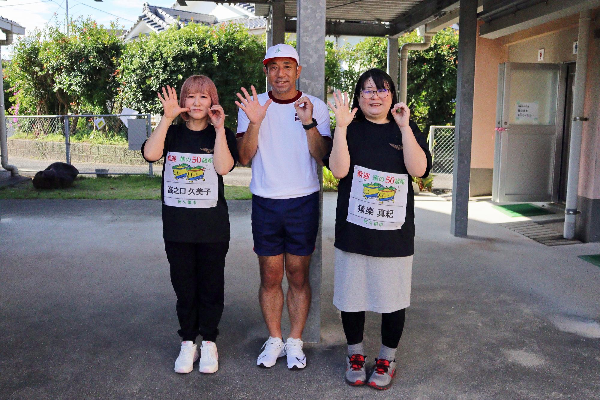 カメラに向け手で50のポーズをとる男女3人の写真