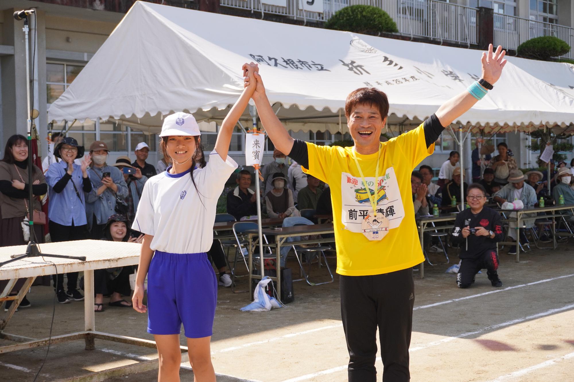 ゴール後に手をつないで小学生と写真を撮る参加者の写真