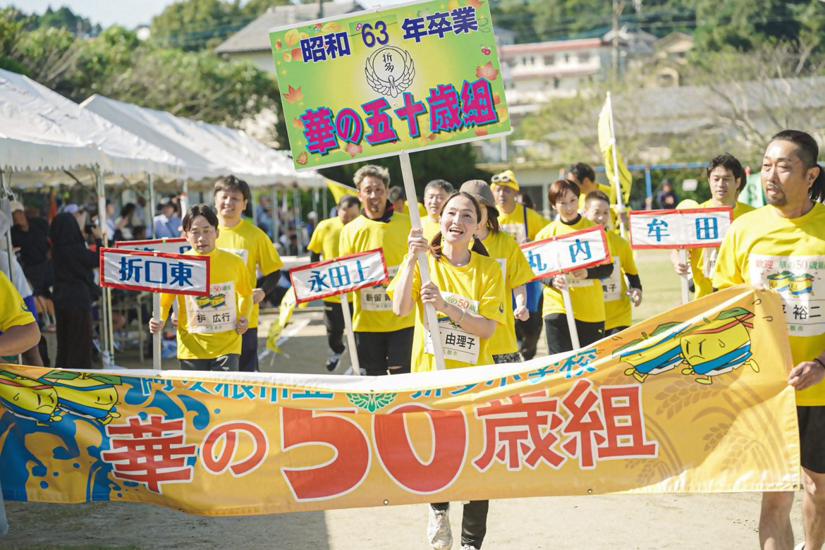 華の50歳組の横断幕を持ちながら入場する参加者の写真