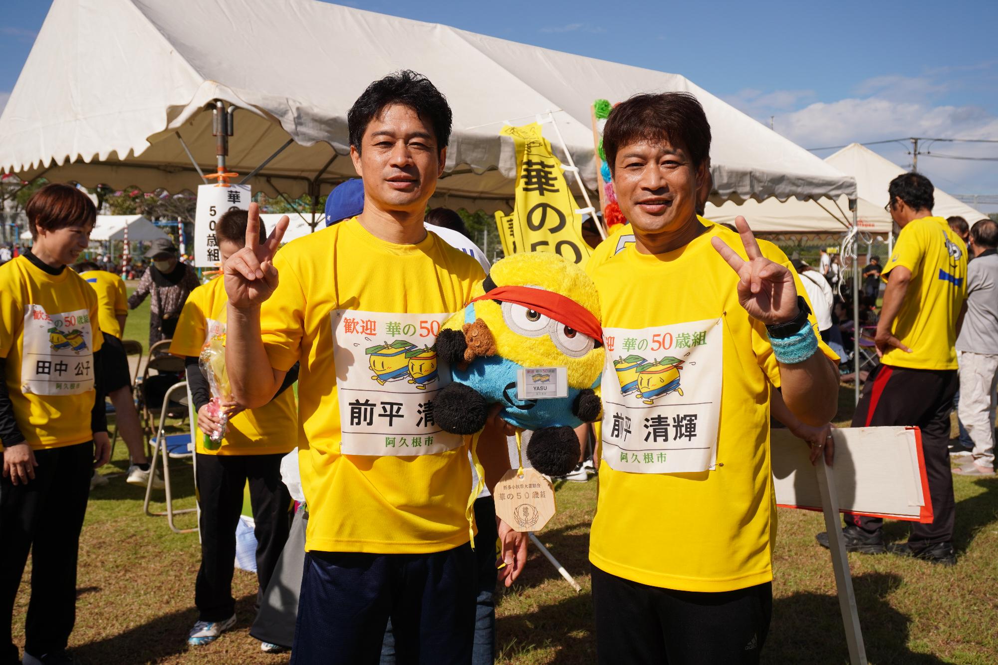 ぬいぐるみ持って写真を撮る男性2人組