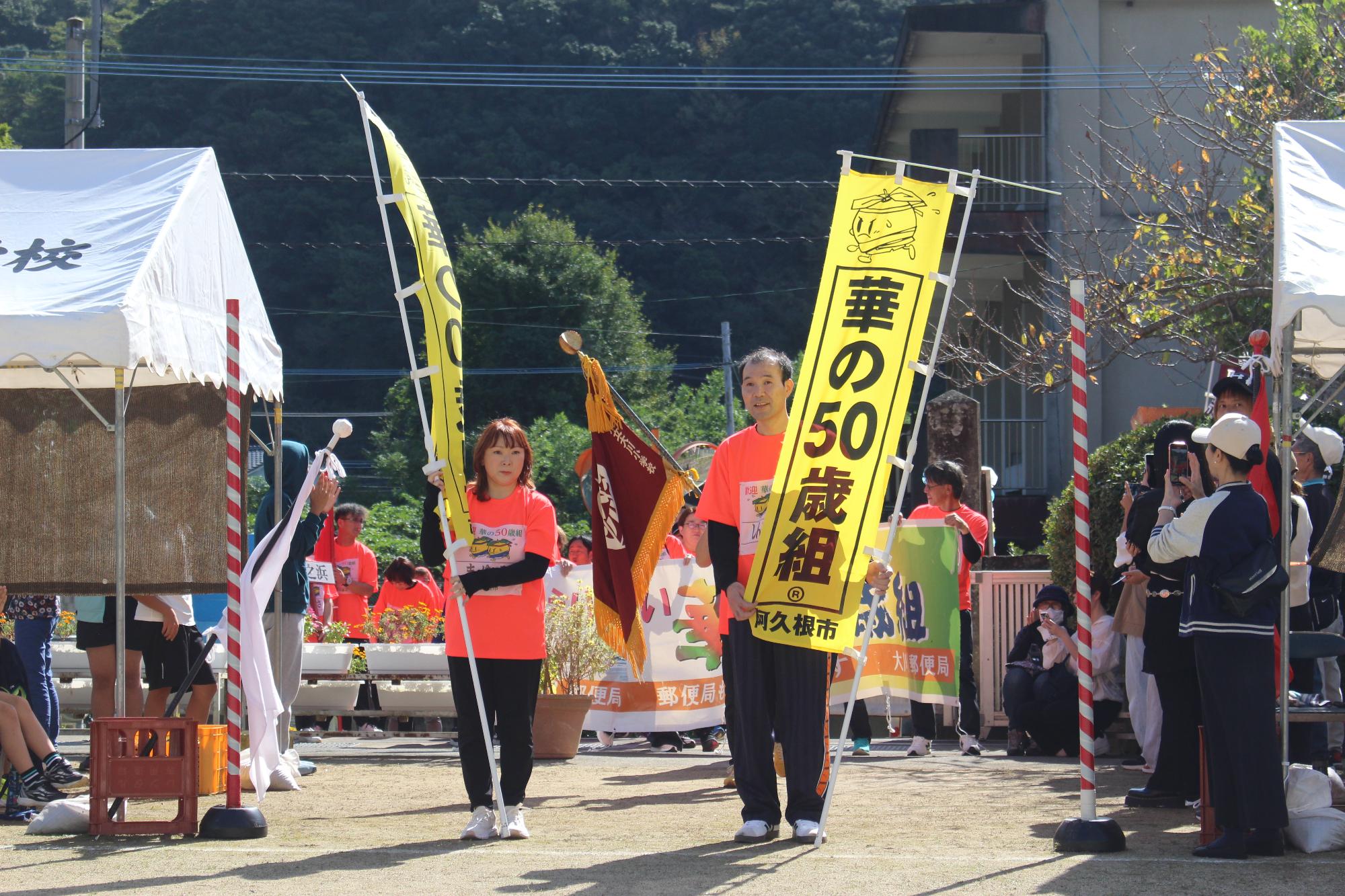 「華の50歳組」と書かれたのぼり旗持って入場待機をする参加者の写真
