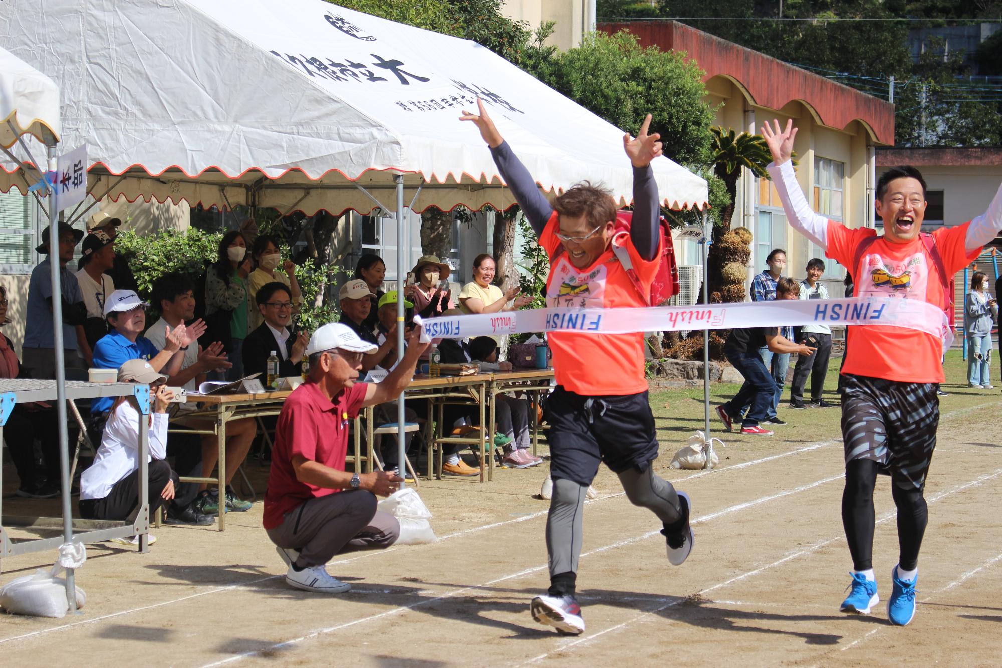 両手を上げてゴールテープを切る参加者の写真