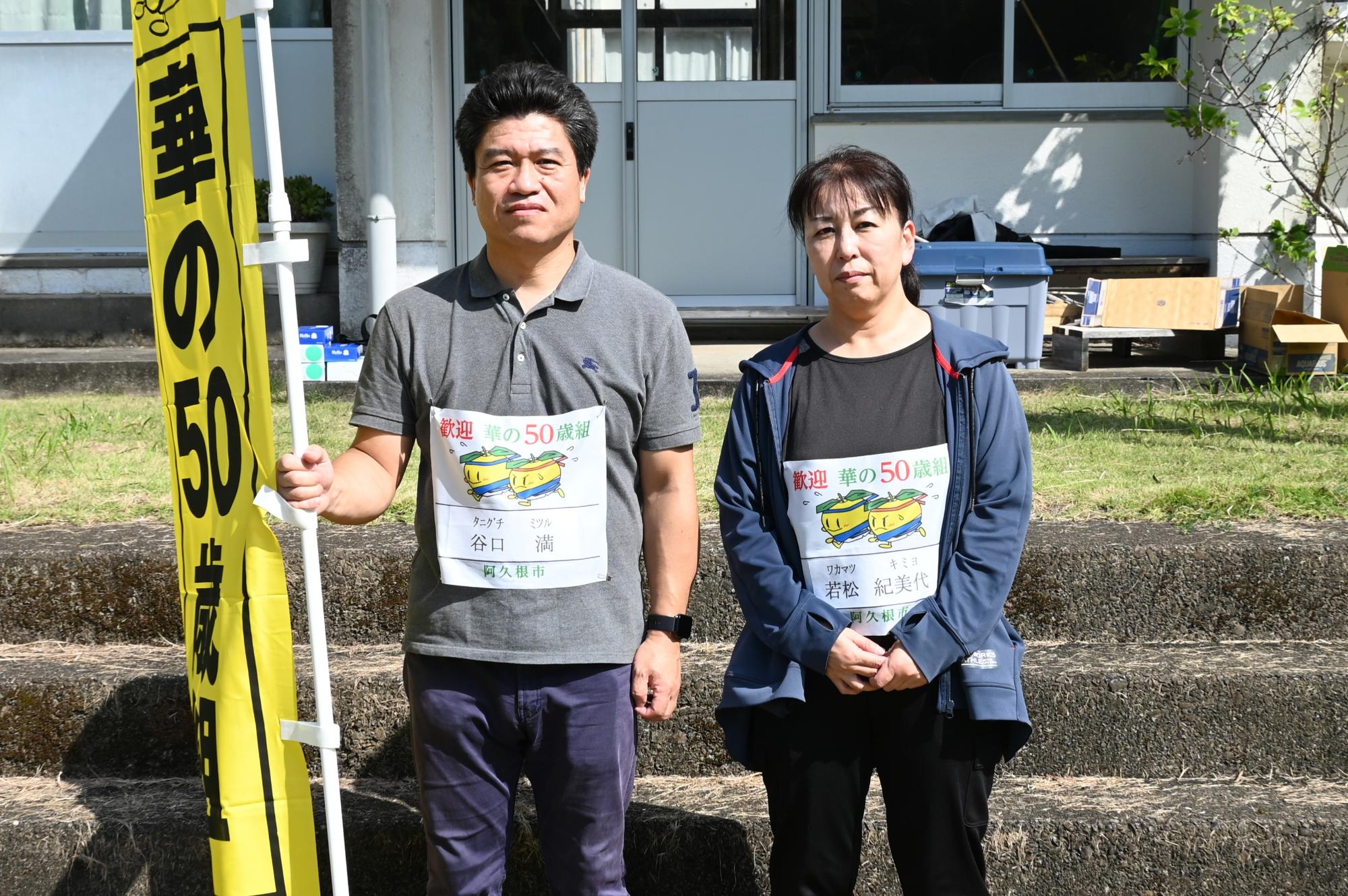 「華の50歳組」と書かれた旗を持って記念撮影を撮る参加者の写真