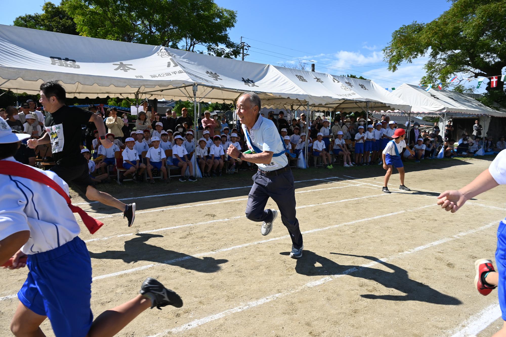 小学生とともにリレーで走る当時の先生の写真
