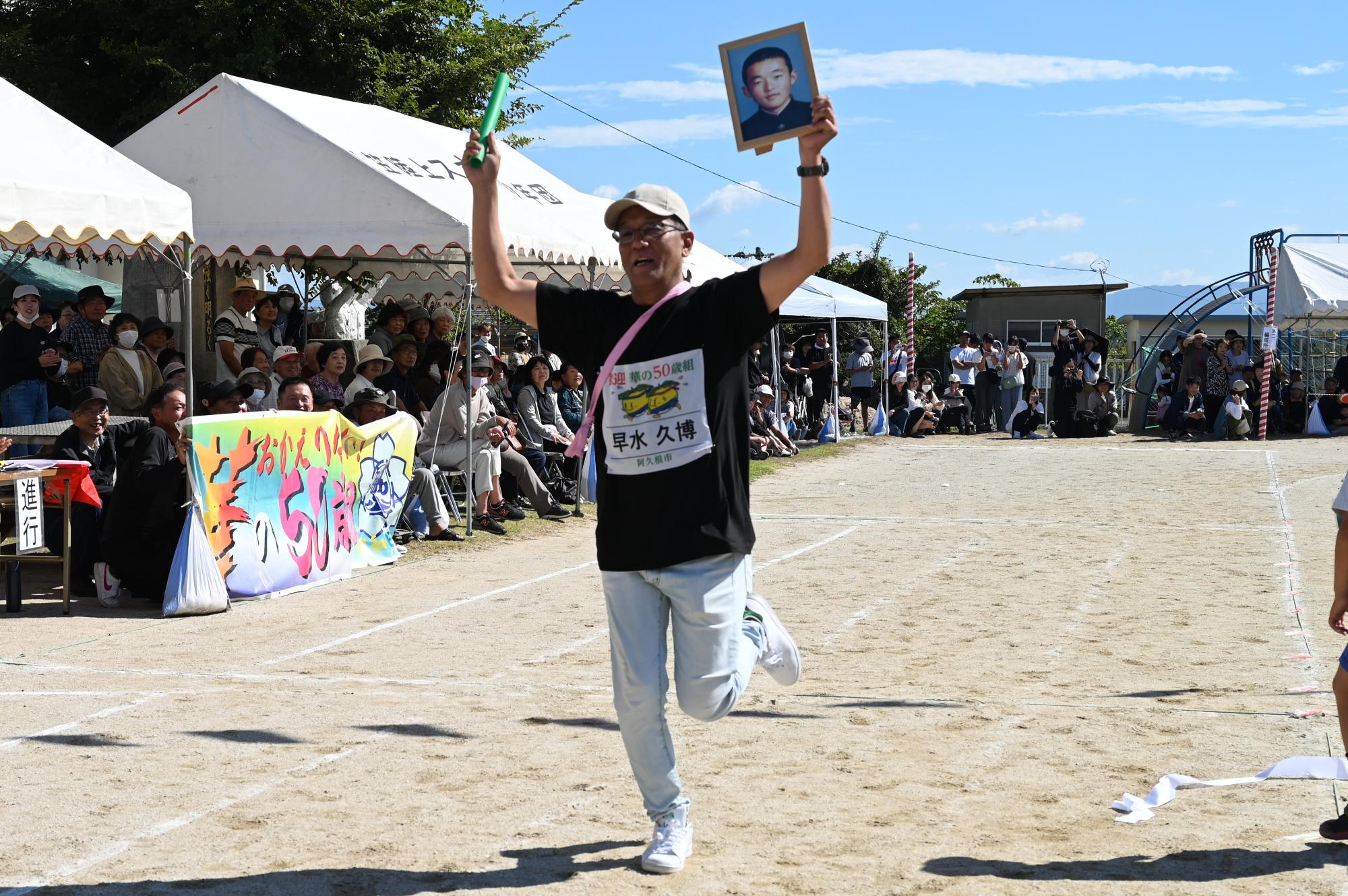 同級生の写真を持ちながらゴールする参加者の写真