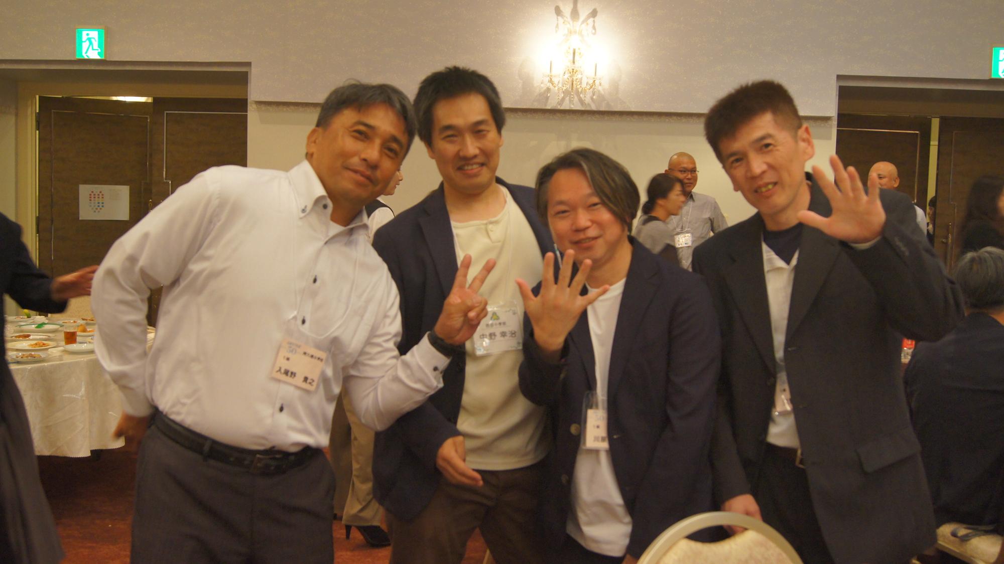 テーブルの近くでポーズをとる男性4人の写真