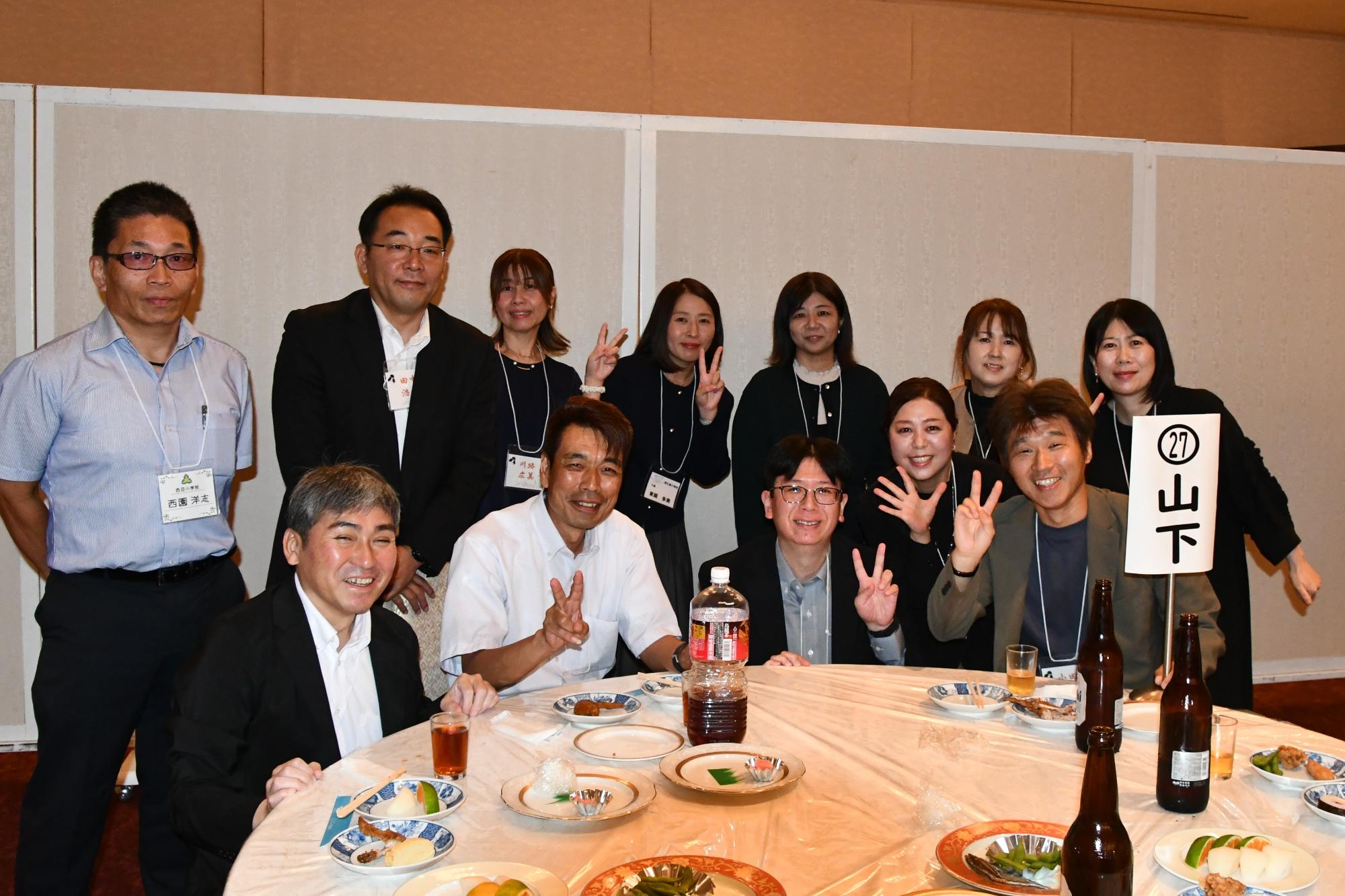 テーブルを囲みポーズをとる西目小出身の男女12人の写真
