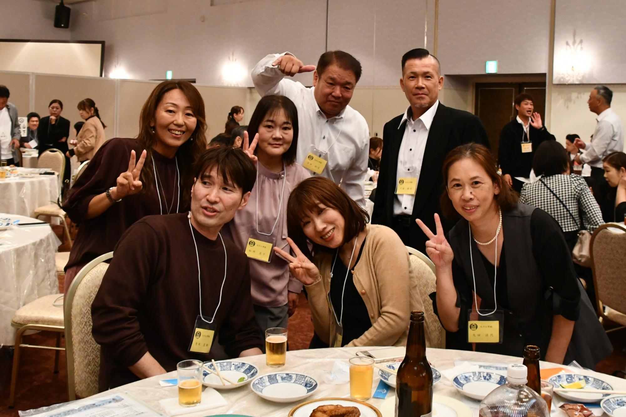テーブルを囲みポーズをとる大川小出身の男女7人の写真