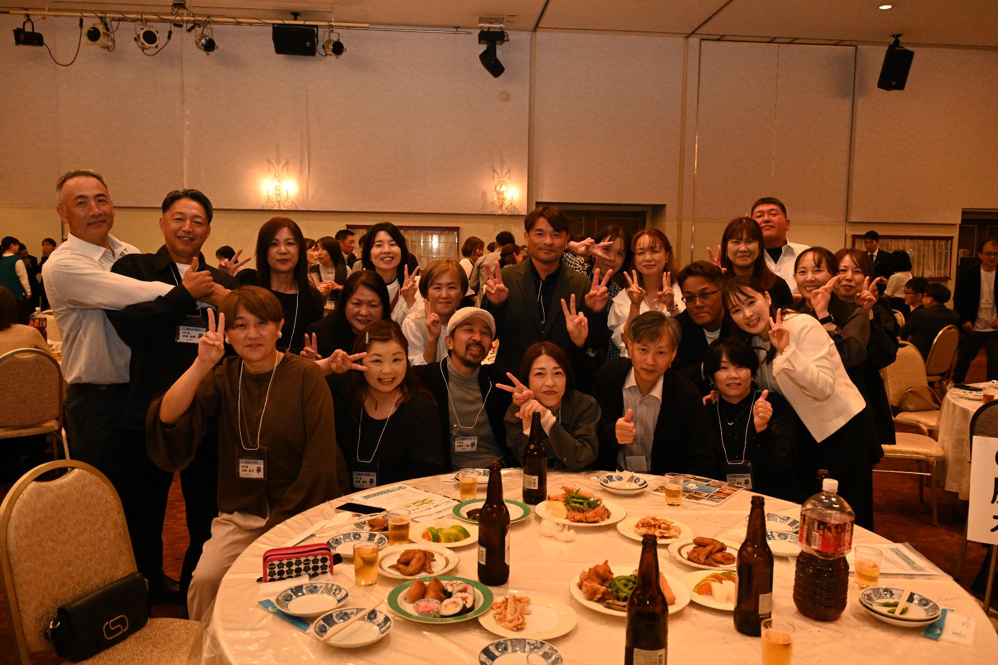 テーブルを囲みピースをする脇本小出身の男女21人の写真