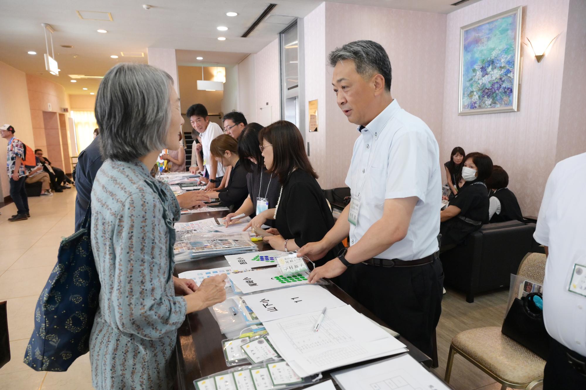 尾崎小出身の参加者たちの写真（受け付けをする女性と受付の男性）