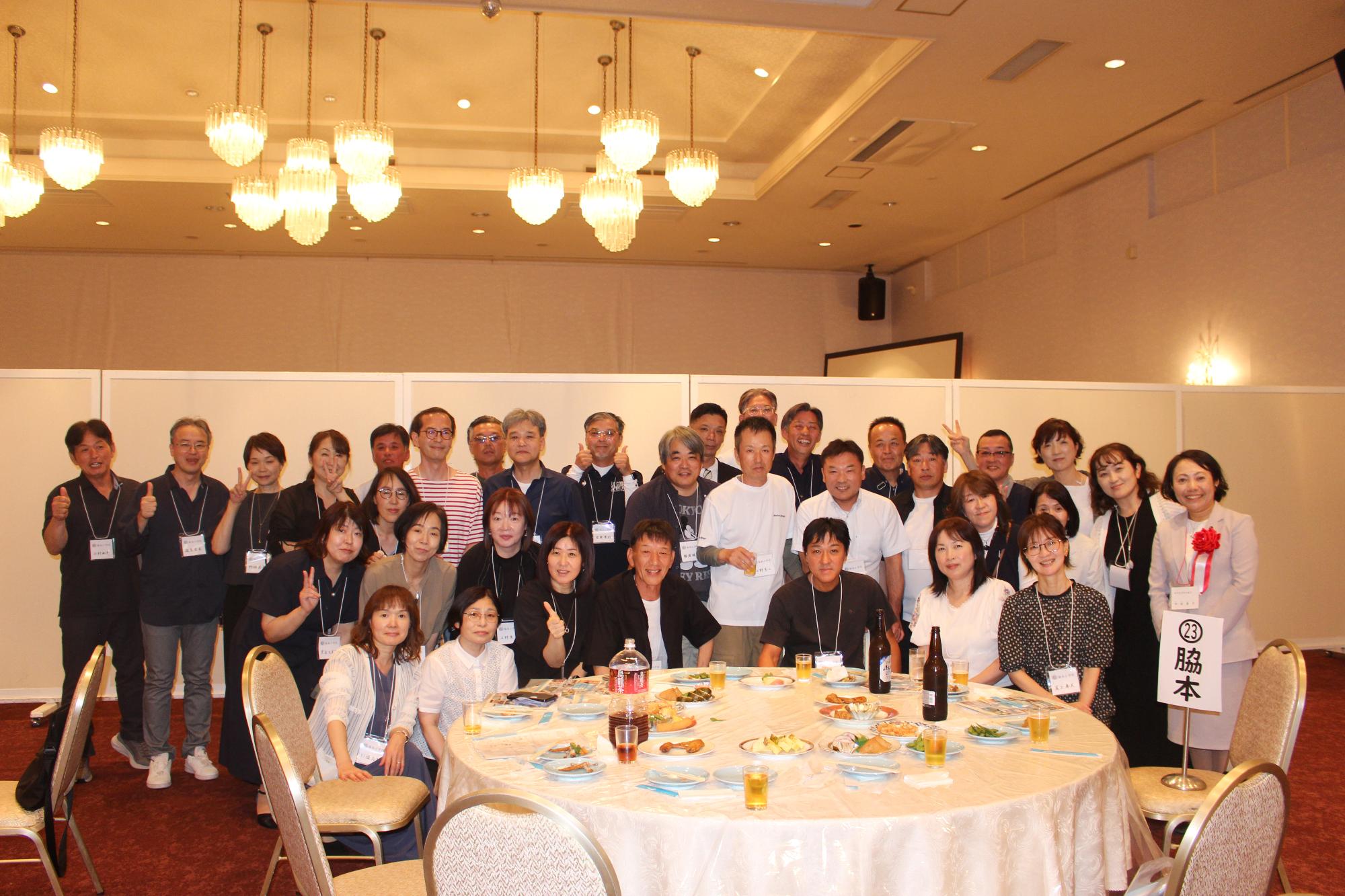 中村県議会議員と脇本小出身の参加者たちの写真（テーブルを囲む34人の男女）