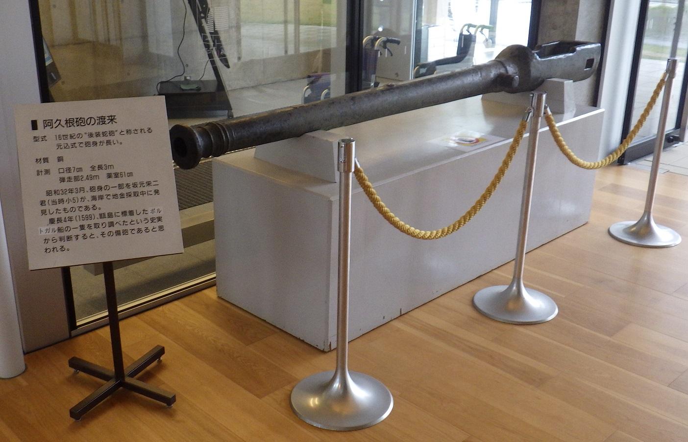 白い頑丈が台に展示されている黒いどっしりとした阿久根砲の写真