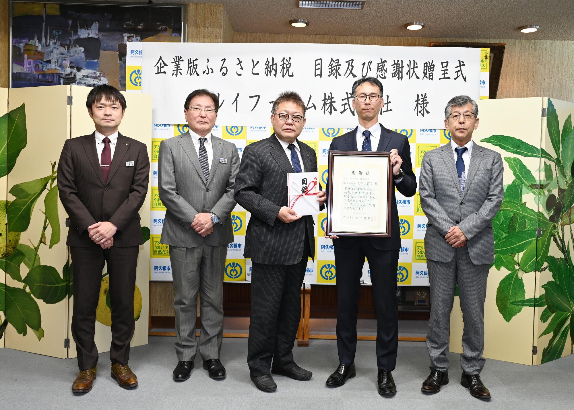 企業版ふるさと納税の感謝状贈呈式でマルイファームの社員らと記念撮影をする西平市長の写真