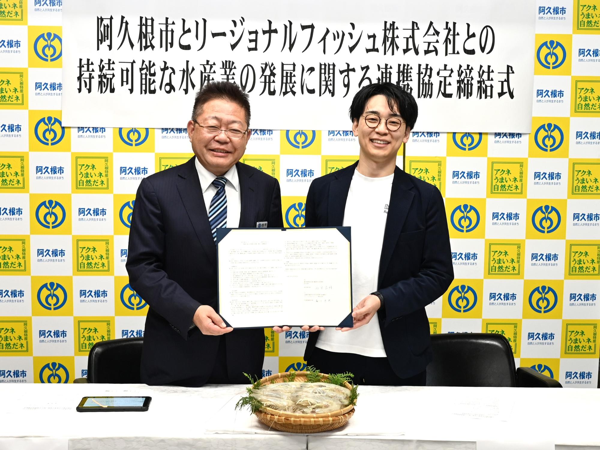 リージョナルフィッシュ株式会社の梅川忠典代表と2人で協定書を持ちながら写真を撮る西平市長
