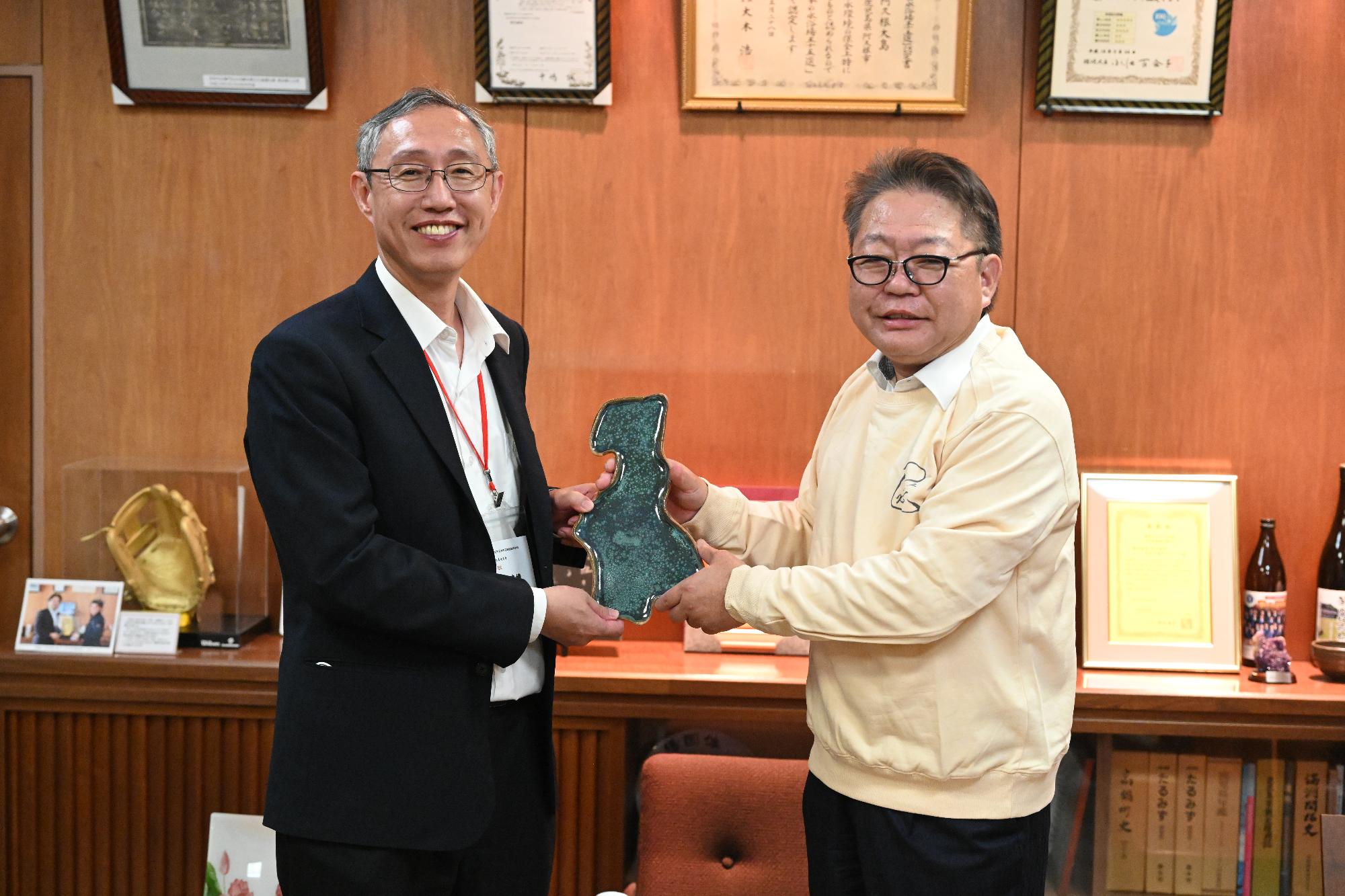 陳校長に阿久根市地形型の皿を贈る西平市長（着用している服は善化高校からの記念品）