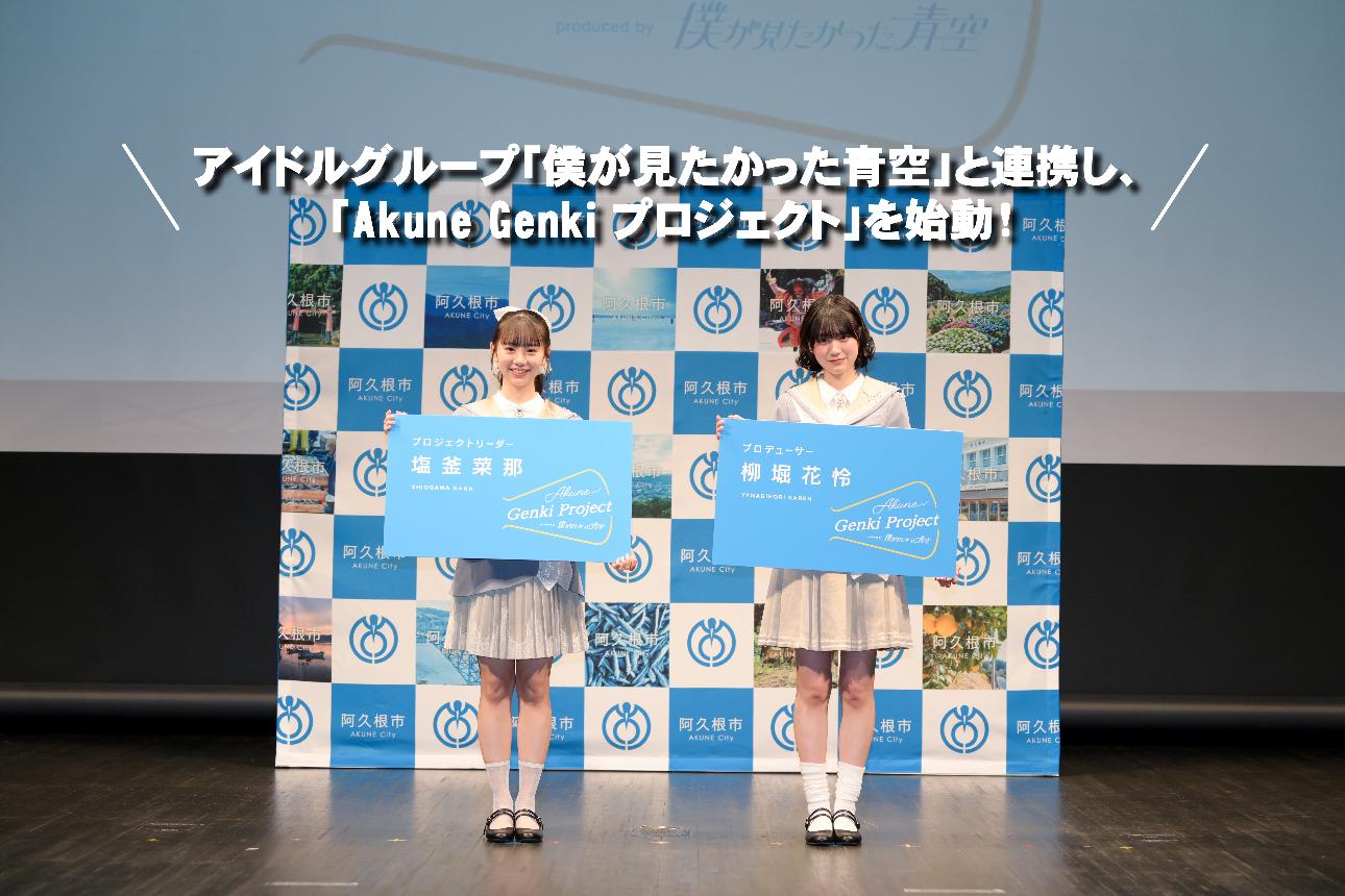 「僕が見たかった青空」の塩釜さんと柳堀さんが特大名刺を持って記念撮影する写真