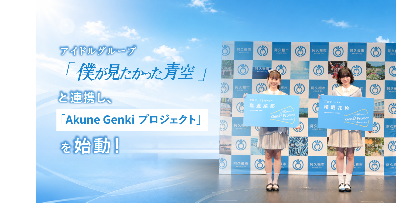 「僕が見たかった青空」の塩釜さんと柳堀さんが特大名刺を持って記念撮影する写真