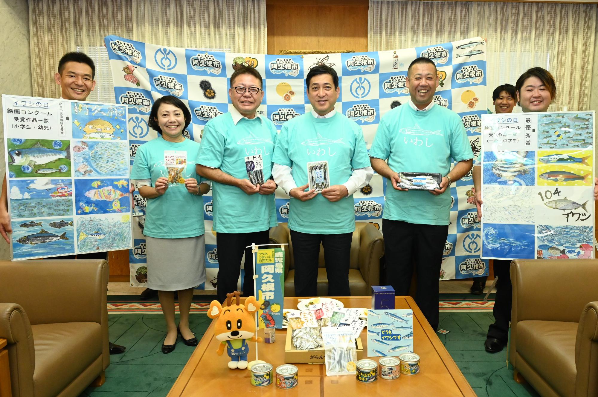 イワシの日の絵画コンクールPRで知事表敬をした際に記念撮影をする塩田鹿児島県知事、西平市長、中村素子県議、関係者らの写真