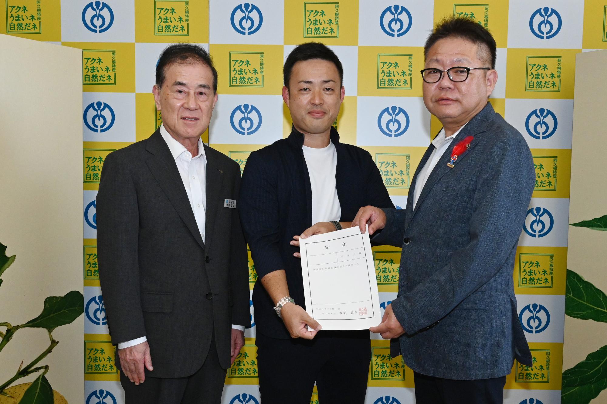 表敬訪問で記念撮影をする写真左から中野教育長、教育委員会委員の原田大輔氏、西平市長の写真